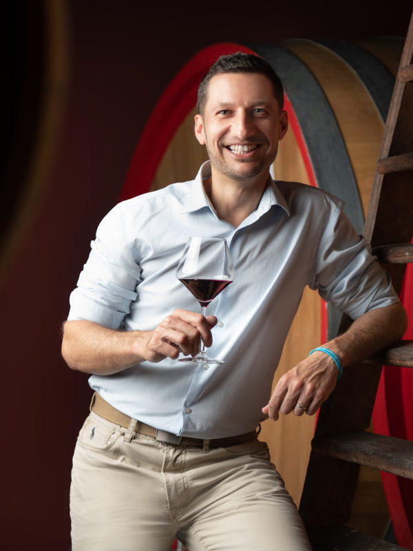 Winemaker Paolo Demarie holding a glass of Barolo wine in his cellar in Barolo DOCG